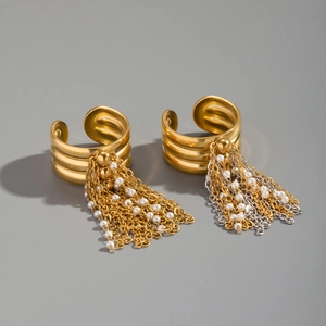Close-up of gold metal fringe rings with white pearls on a neutral grey background