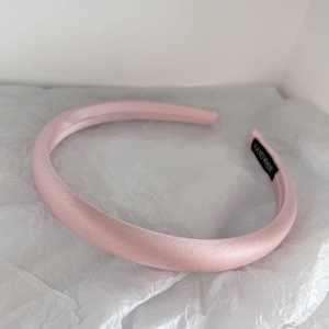 Detailed macro view of pink satin padded headband with handmade label on soft background