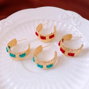 Detail of vintage C-shape earrings with hammered metal and colorful thread wrapping