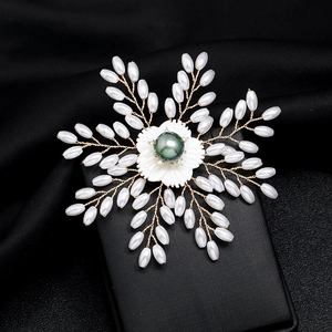 Detailed close-up of a luxury snowflake brooch with white pearls and a black pearl center