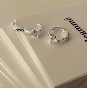 Detailed view of silver hoop earrings featuring sparkling heart-shaped zircon stones