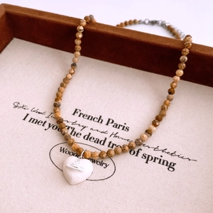 Macro shot of vintage style beaded necklace featuring a white heart Saturn orb pendant