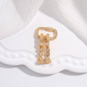 Elegant gold earrings with sparkling crystals and carabiner hooks on ceramic tray
