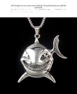 Macro shot of polished silver shark pendant with detailed teeth on a black background