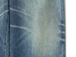 Detailed macro view of vintage blue washed denim fabric with distinct whiskers and twill texture