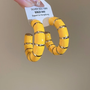 Macro shot of 925 silver bamboo-style hoop earrings with yellow glaze and metallic stripes