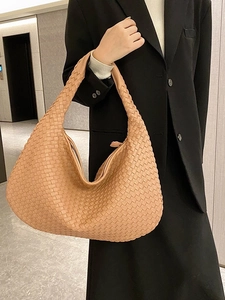 Elegant woven leather tote bag in camel beige for women, shown in a modern interior setting