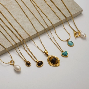 Golden necklaces set with pearls, tiger eye stones and turquoise on stone display