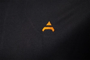 Detailed macro shot of high-quality black knit fabric with vibrant orange embroidery logo