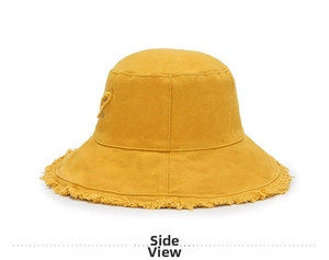 Detail of yellow cotton bucket hat with distressed frayed edges and heart patch