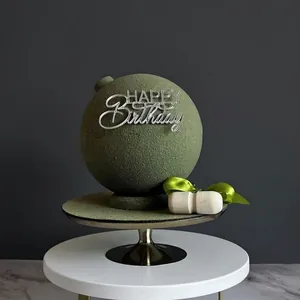 Detailed view of moss green frosted ball cake with silver Happy Birthday acrylic topper