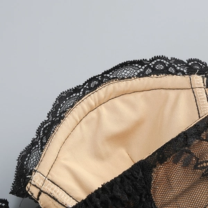 Dettaglio del pizzo nero e della fodera beige di un abito corto con schiena scoperta