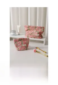 Detail of pink embroidered flower makeup bags with fringe edges and H&R BAG logo tags