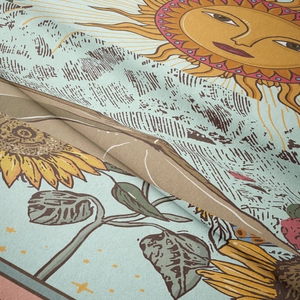 Close-up of bohemian tapestry fabric showing sun face and sunflower print details