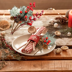 Artificial Christmas picks with red berries and pine cones on a rustic wood background