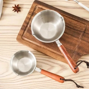 Close-up of stainless steel butter warmers with wooden handles and leather loops