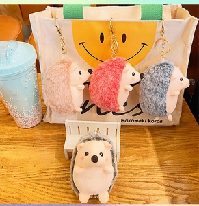 Detail of colorful plush hedgehog keychains with metal clasps on a canvas bag