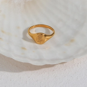 Macro detail of gold flower signet ring displayed inside a white decorative seashell
