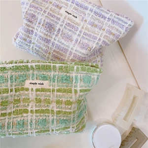Detail of tweed makeup bags with gold thread textures and simple wish label