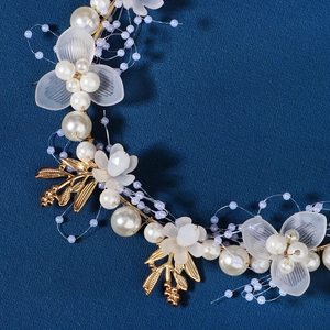 Detailed close-up of handmade bridal headband with gold leaves, pearls and white flowers