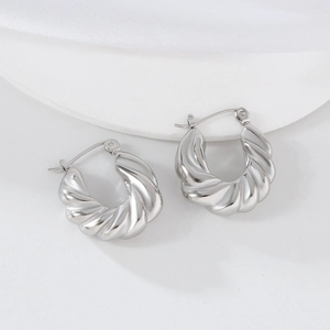 Gros plan de boucles d'oreilles torsadées en forme de U argentées sur un socle blanc