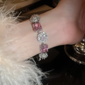 Detail of a silver flower bracelet with pink square gemstones on a model's wrist
