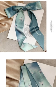 Detail of teal gradient silk scarf featuring crane print and Love Yourself lettering