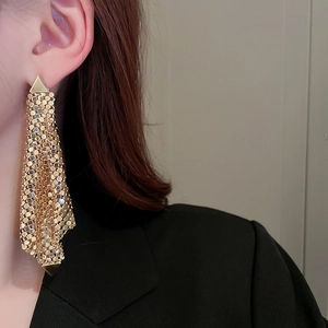 Gros plan de boucles d'oreilles dorées en maille triangulaire portées par un mannequin