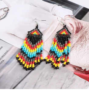 Detail of bohemian long beaded tassel earrings in red, yellow and blue on a magazine