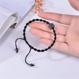 Detail of adjustable black woven bracelet with square hematite stone on person wrist