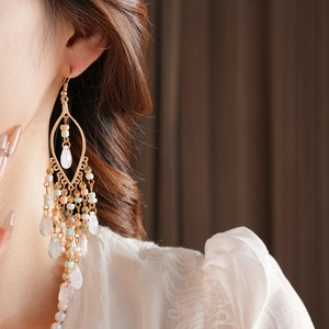 Macro detail of long bohemian beaded tassel earrings with pastel teardrop charms on model