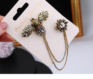 Macro detail of retro bee and flower brooch set with golden chains and faceted amber gems