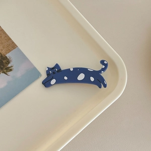 Detailed view of a cute navy blue cat hair clip with white dots on a beige tray