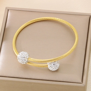 Detail of gold twisted cable cuff bangle with shimmering diamond-encrusted sphere ends