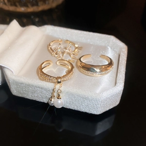Detail of gold plated ring set with zircon pavé, pearls, and elegant long tassels