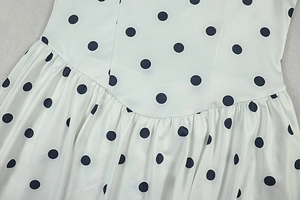 Macro detail of polka dot print fabric with waist pleats and smooth fabric texture