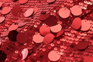 Close-up of sparkling red sequins on fabric with vibrant metallic shine and texture