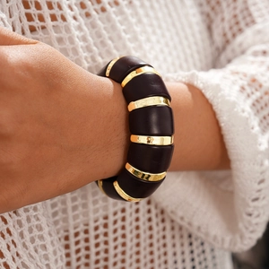 Gros plan sur les segments en acrylique rétro et les anneaux dorés du bracelet élastique