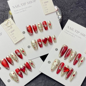 Oxblood red cat-eye press-on nails with ruby heart accents and sparkling crystals