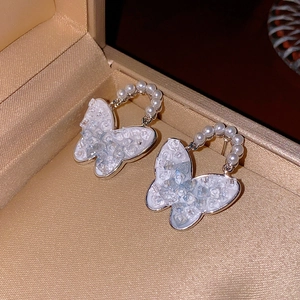 Close-up of asymmetric butterfly earrings with sparkling crystals and pearl details