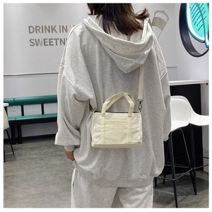Detailed back view of a retro off-white corduroy Boston bag worn by a model in a cafe