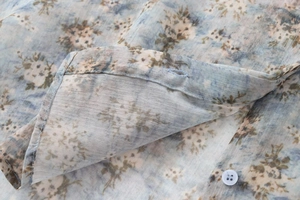 Détail de chemise en popeline à fleurs bleues montrant les coutures et le bouton blanc