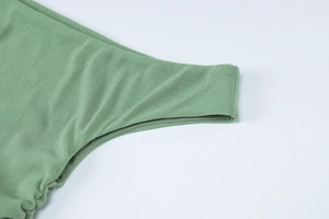 Macro view of green waffle knit fabric texture and high-density side seam stitching