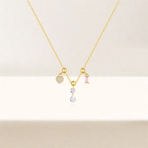 Detail of gold chain necklace with pink rectangle and heart zircon pendants