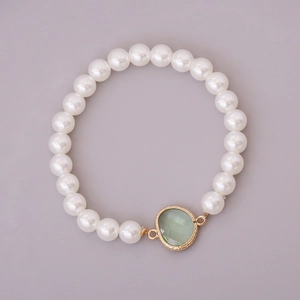 Detail of white glass pearls bracelet featuring a faceted light green gemstone pendant