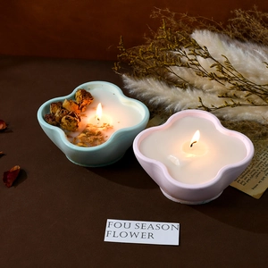 Close-up of four-leaf clover ceramic candle jars with dried rose petals and warm light