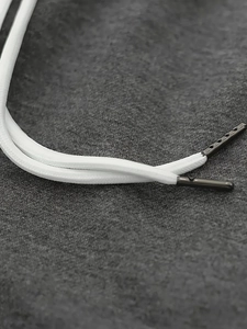 Détail du cordon en coton blanc avec des embouts en métal gris foncé et design dentelé
