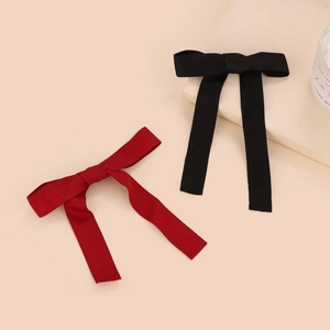 Elegant red and black ribbon bow hair clips with long streamers on a neutral surface