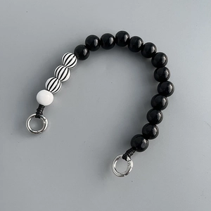 Detail of checkered and solid wood beads phone strap with silver spring rings