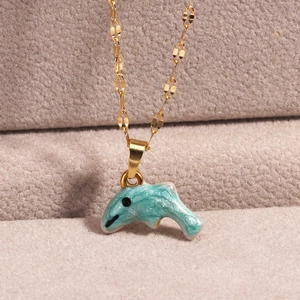 Macro shot of gold dolphin necklace pendant with blue glitter enamel and fine oval links